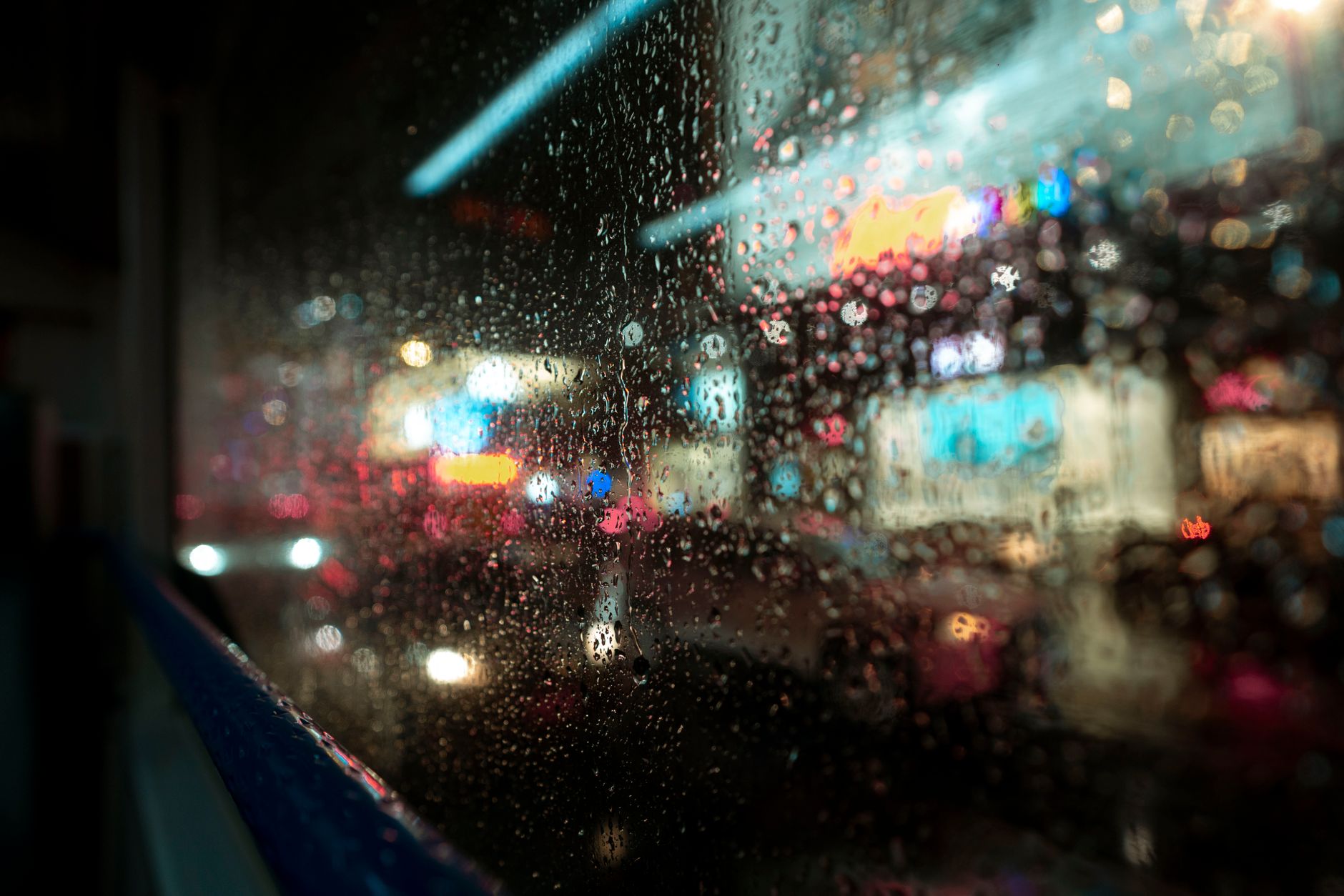 Rain streaking a train window above a dark landscape